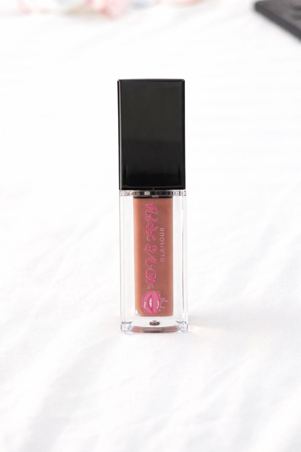 Vanilla Latte Glow glossy lip gloss bottle on a white surface, ideal for little coffee lovers.