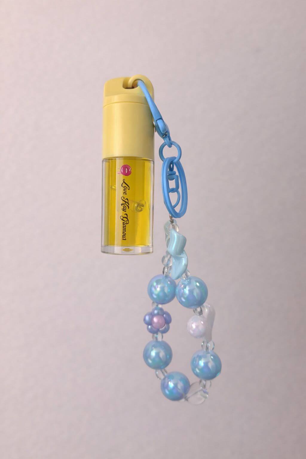 Mango Pop kids' fruity gloss with juicy mango flavor in a yellow tube, adorned with a beaded keychain.